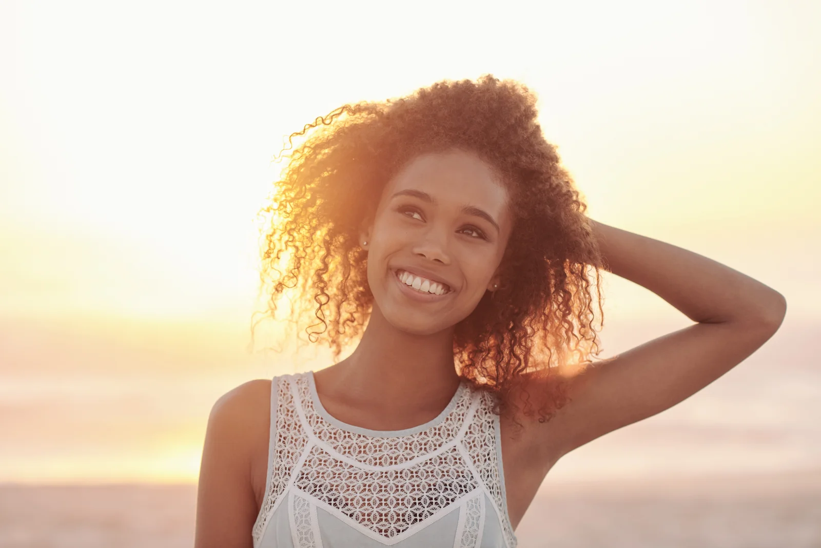 A smiling woman with curly hair in the evening sunlight